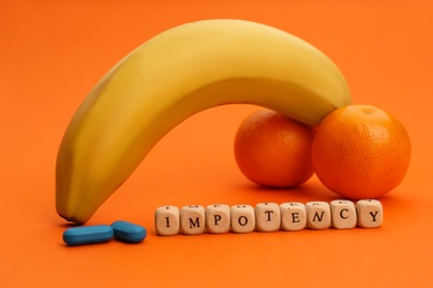 Photo of Fruits symbolizing male sexual organ, pills and word IMPOTENCY on orange background