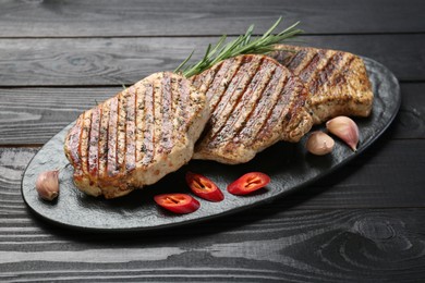 Delicious grilled pork steaks with spices on dark wooden table