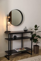 Photo of Console table with decor and mirror on white wall in hallway. Interior design