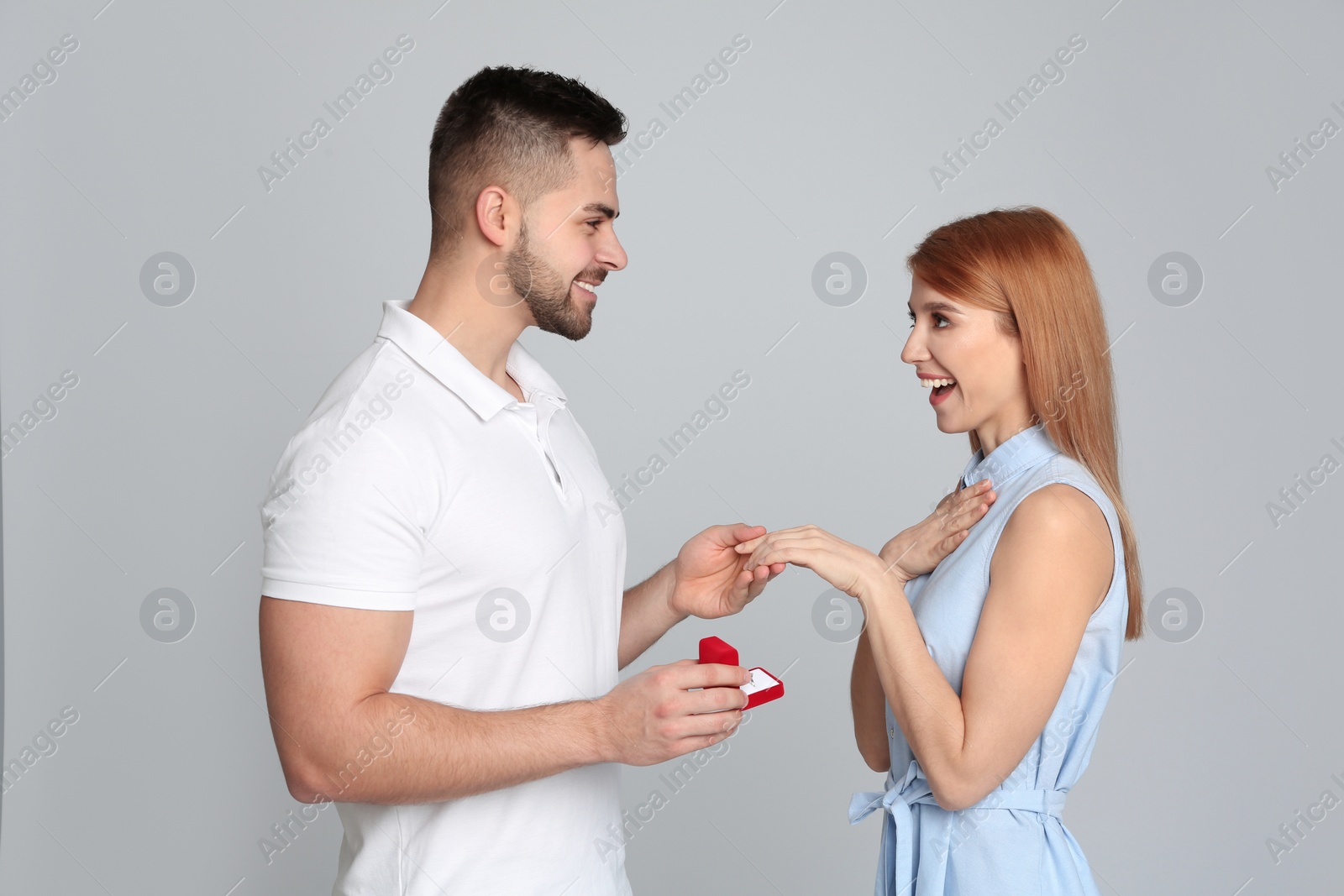 Photo of Man with engagement ring making marriage proposal to girlfriend on light grey background