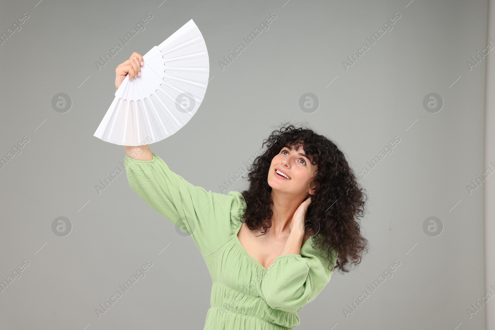 Photo of Happy woman holding hand fan on light grey background