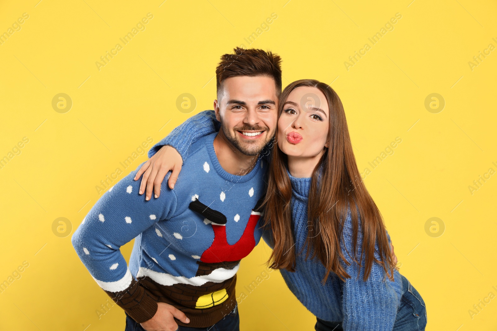 Photo of Couple wearing Christmas sweaters on yellow background