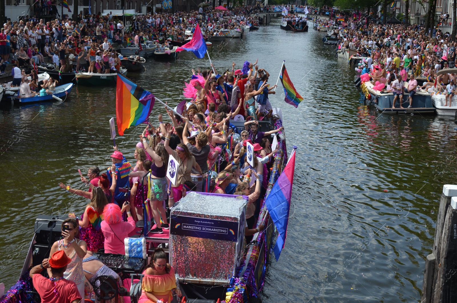 Photo of AMSTERDAM, NETHERLANDS - AUGUST 06, 2022: Many people in boats at LGBT pride parade on river