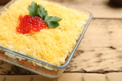 Traditional russian salad Mimosa served on wooden table, closeup