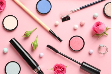 Flat lay composition with products for decorative makeup on pastel pink background