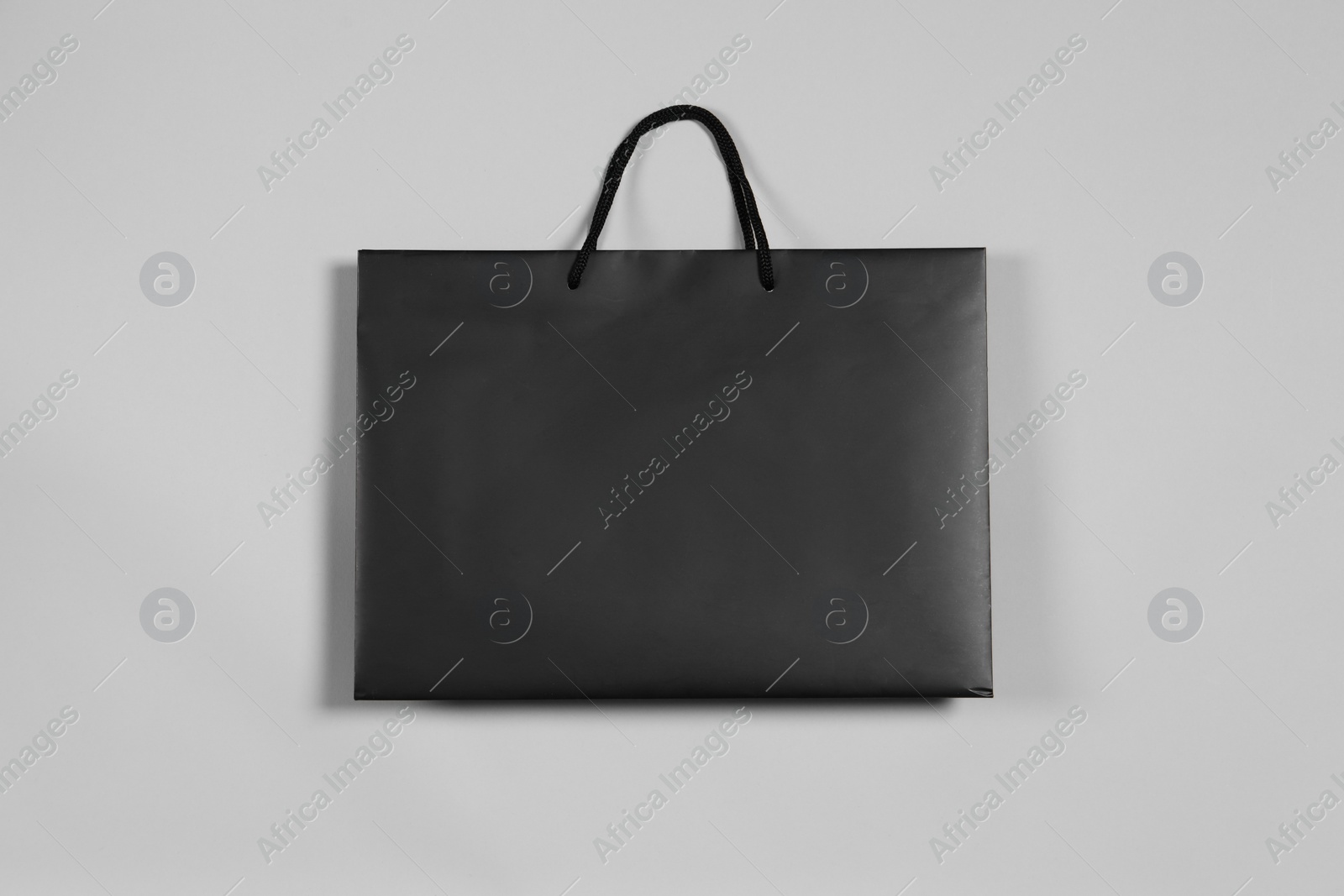 Photo of One black paper shopping bag on grey background, top view