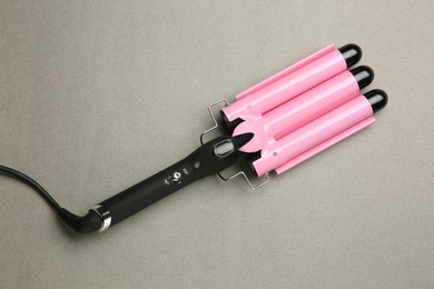 Photo of Modern triple curling hair iron on grey background, top view