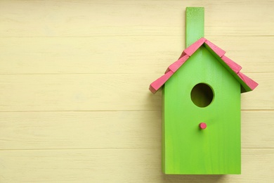 Beautiful green bird house on pale yellow wooden background, space for text