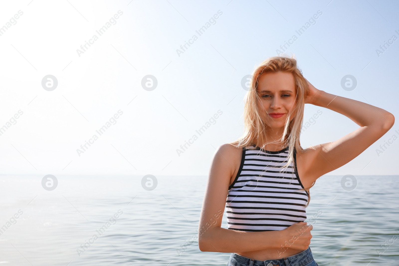 Photo of Beautiful young woman near sea on sunny day in summer, space for text