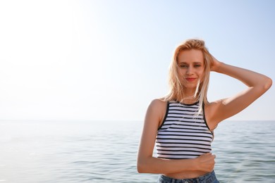 Photo of Beautiful young woman near sea on sunny day in summer, space for text