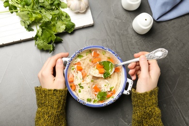 Photo of Woman eating fresh homemade chicken soup at table, top view