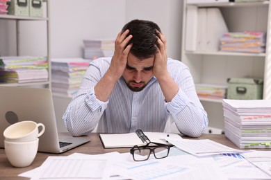 Overwhelmed man sitting at table in office