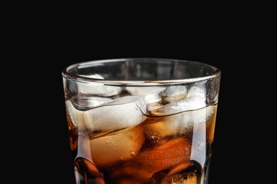 Glass of tasty refreshing cola with ice cubes on black background, closeup