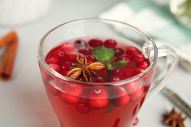 Tasty hot cranberry tea with mint and anise in glass cup, closeup