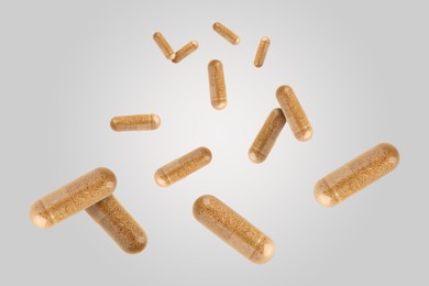 Image of Vitamin. Capsules falling on light grey background