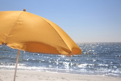 Orange beach umbrella near sea on sunny day