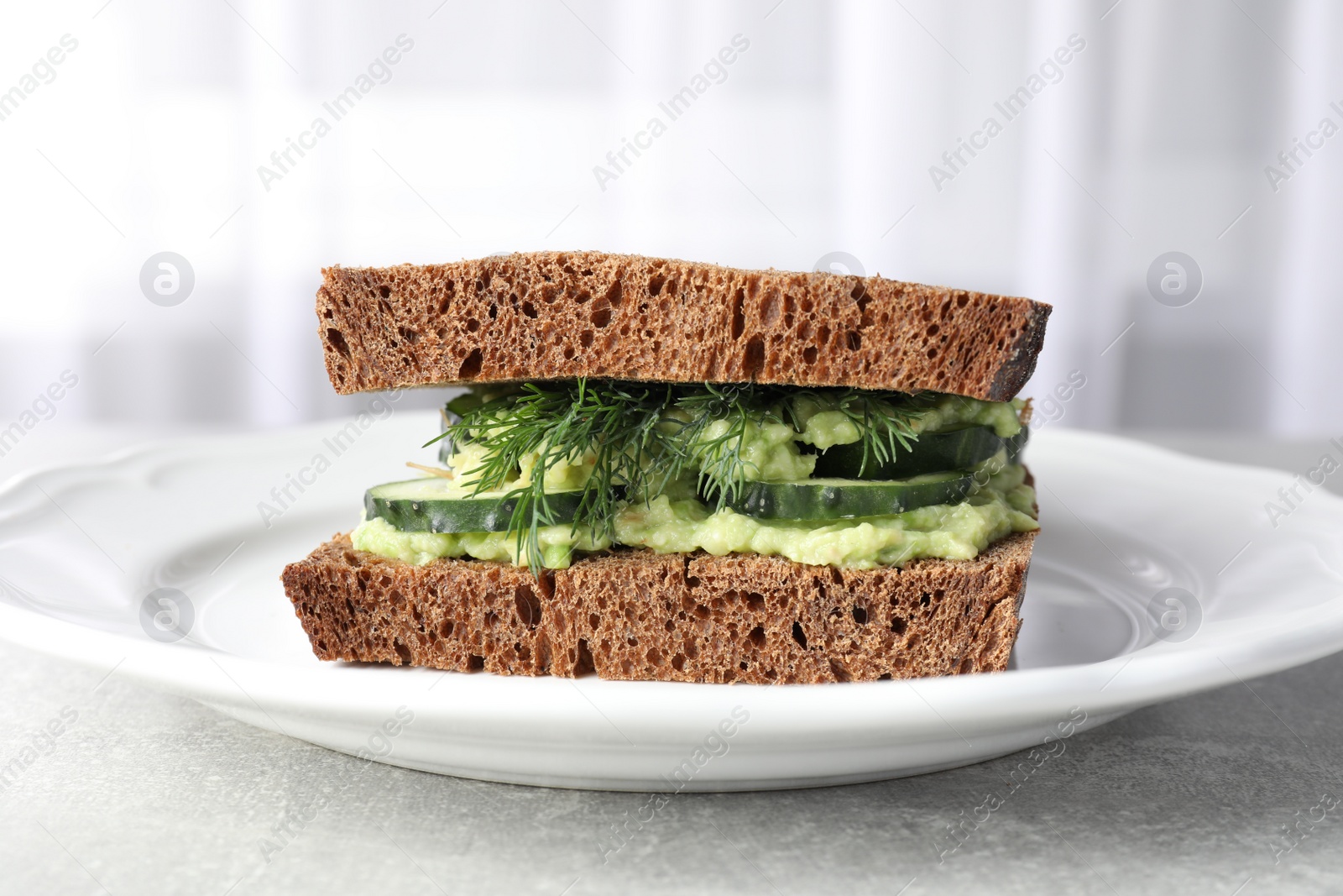 Photo of Tasty sandwich with cucumber, cream cheese and dill on grey table, closeup