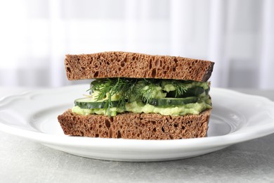 Tasty sandwich with cucumber, cream cheese and dill on grey table, closeup