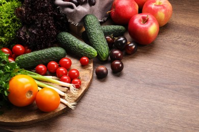 Different fresh ripe vegetables and fruits on wooden table, space for text