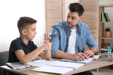 Photo of Dad helping his son with homework in room