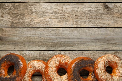 Many delicious fresh bagels on wooden table, flat lay. Space for text