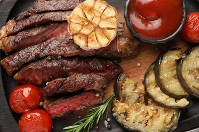 Photo of Delicious grilled beef with vegetables, tomato sauce and spices on tray, top view