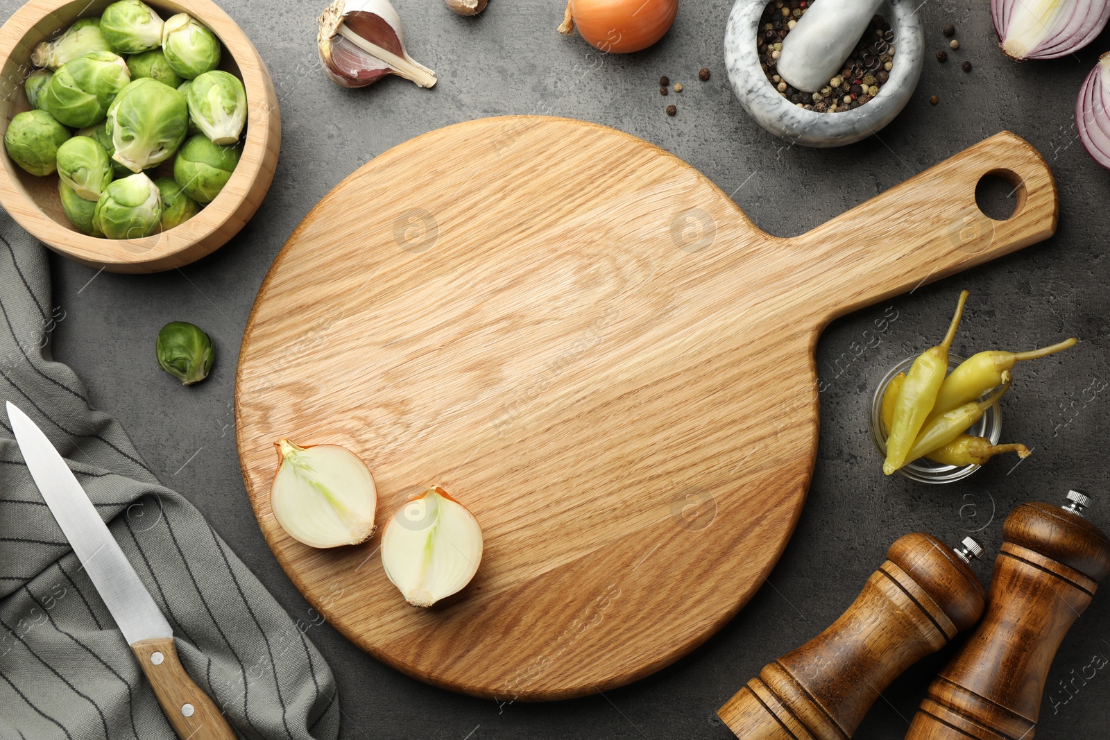 Photo of Flat lay composition with wooden cutting board and products on dark textured table