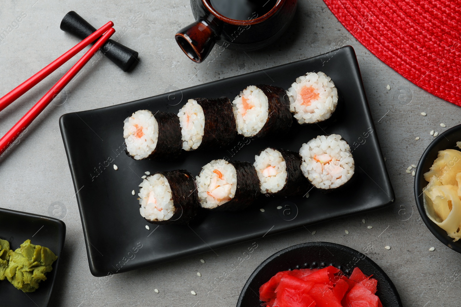 Photo of Tasty sushi rolls served on grey table, flat lay