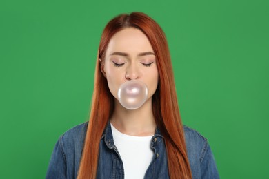Photo of Beautiful woman blowing bubble gum on green background