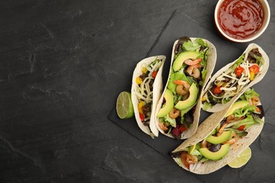 Photo of Delicious tacos, lime and sauce on black table, flat lay. Space for text