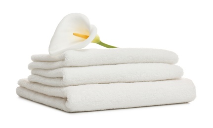 Stack of clean folded towels with flower on white background