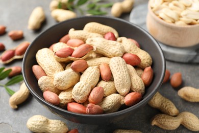 Photo of Fresh unpeeled peanuts in bowl on grey table, closeup