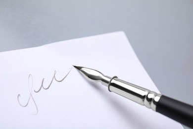 Photo of Signing on sheet of paper with fountain pen against light grey background, closeup. Space for text