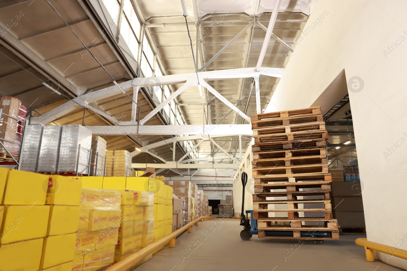 Image of Modern manual forklift with wooden pallets in warehouse