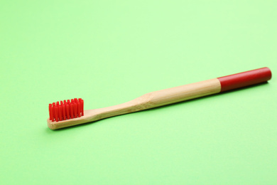 Photo of Natural bamboo toothbrush with soft bristles on green background