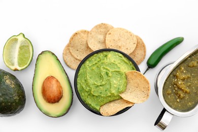 Photo of Delicious guacamole made of avocados, nachos and green pepper on white background, top view