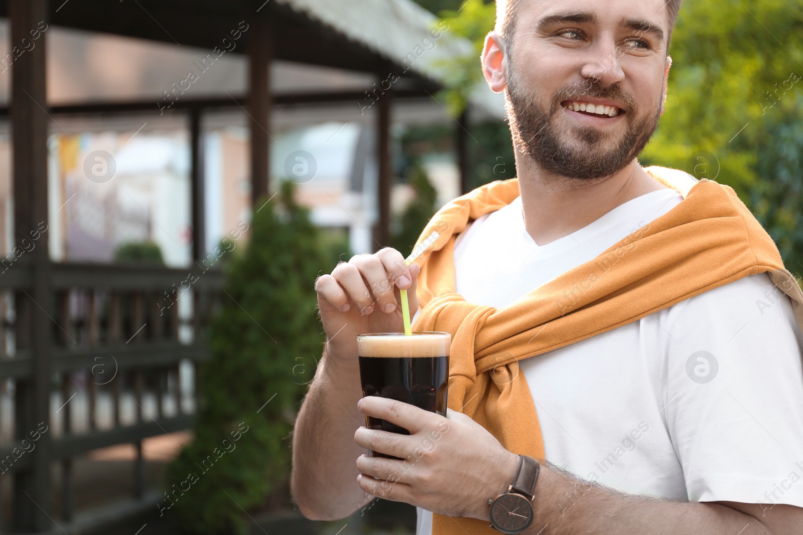 Photo of Handsome man with cold kvass outdoors. Traditional Russian summer drink