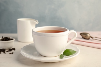 Cup of delicious tea with saucer on table