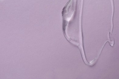 Photo of Clear cosmetic gel on light violet background, top view. Space for text