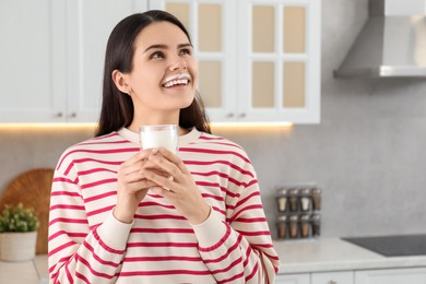 Photo of Happy woman with milk mustache holding glass of tasty dairy drink in kitchen. Space for text
