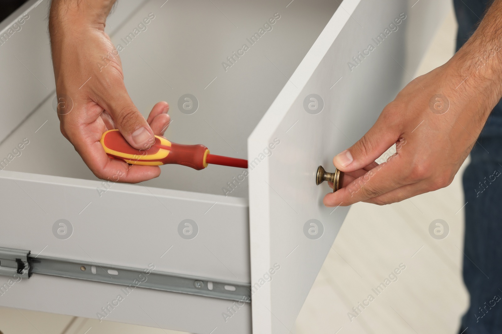 Photo of Man with screwdriver assembling drawer, closeup view