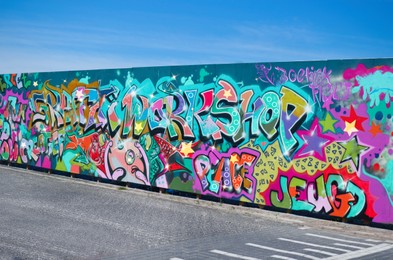 Wall with bright colorful graffiti on sunny day