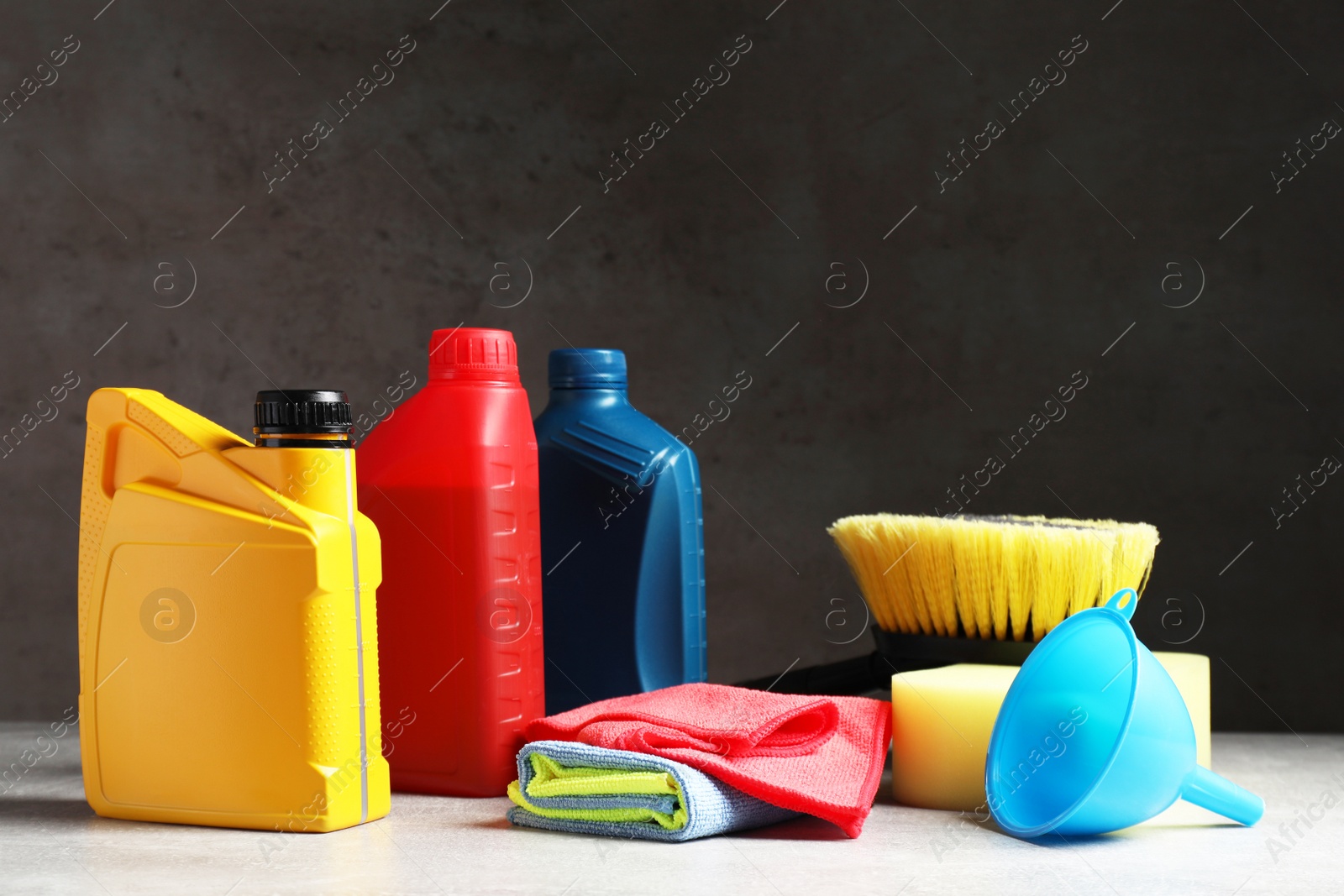 Photo of Car cleaning products, canister with motor oil and microfiber fabric on light grey table