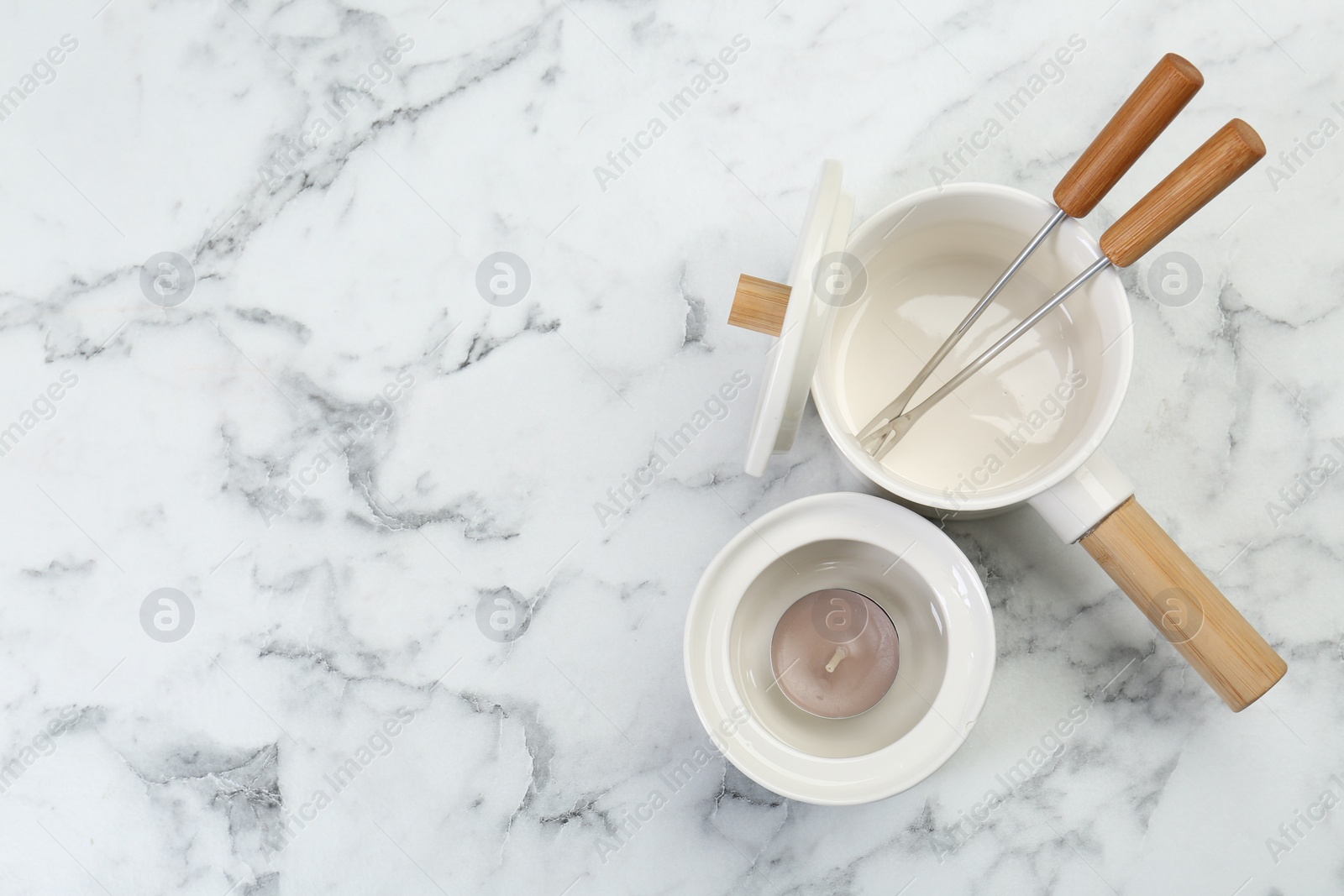 Photo of Fondue set on white marble table, flat lay. Space for text