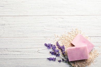 Handmade soap bars, oatmeal and lavender on white wooden background, top view with space for text