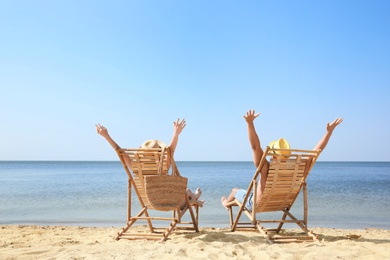 Photo of Young couple relaxing in deck chairs on beach