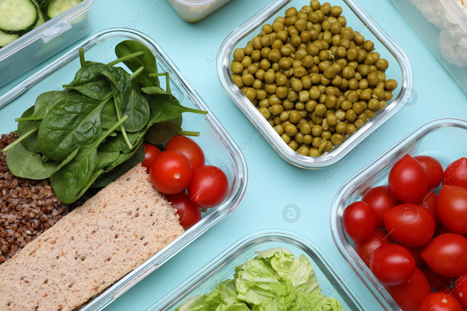 Photo of Glass containers with different fresh products on light blue background, flat lay