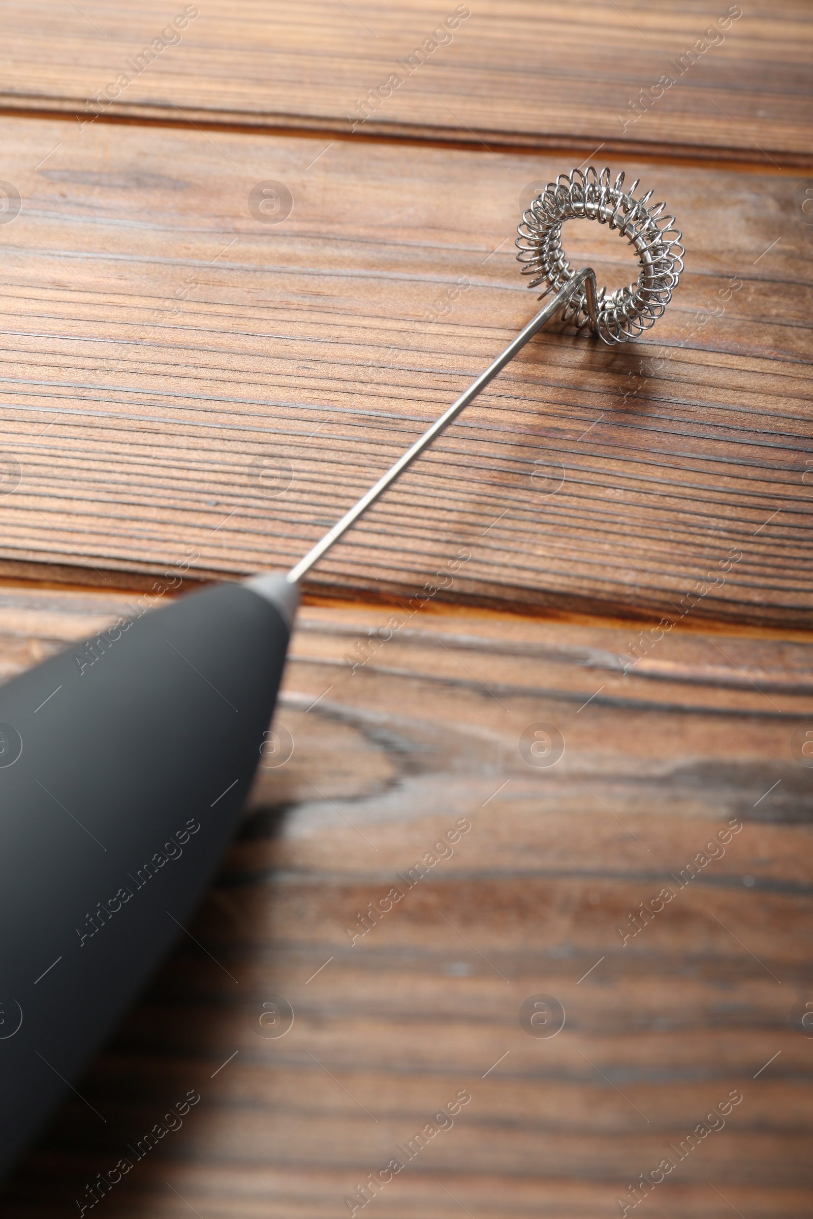 Photo of Black milk frother wand on wooden table, closeup