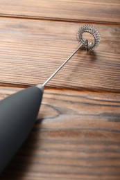 Photo of Black milk frother wand on wooden table, closeup