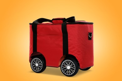 Image of Red thermo bag on wheels against orange background. Food delivery service